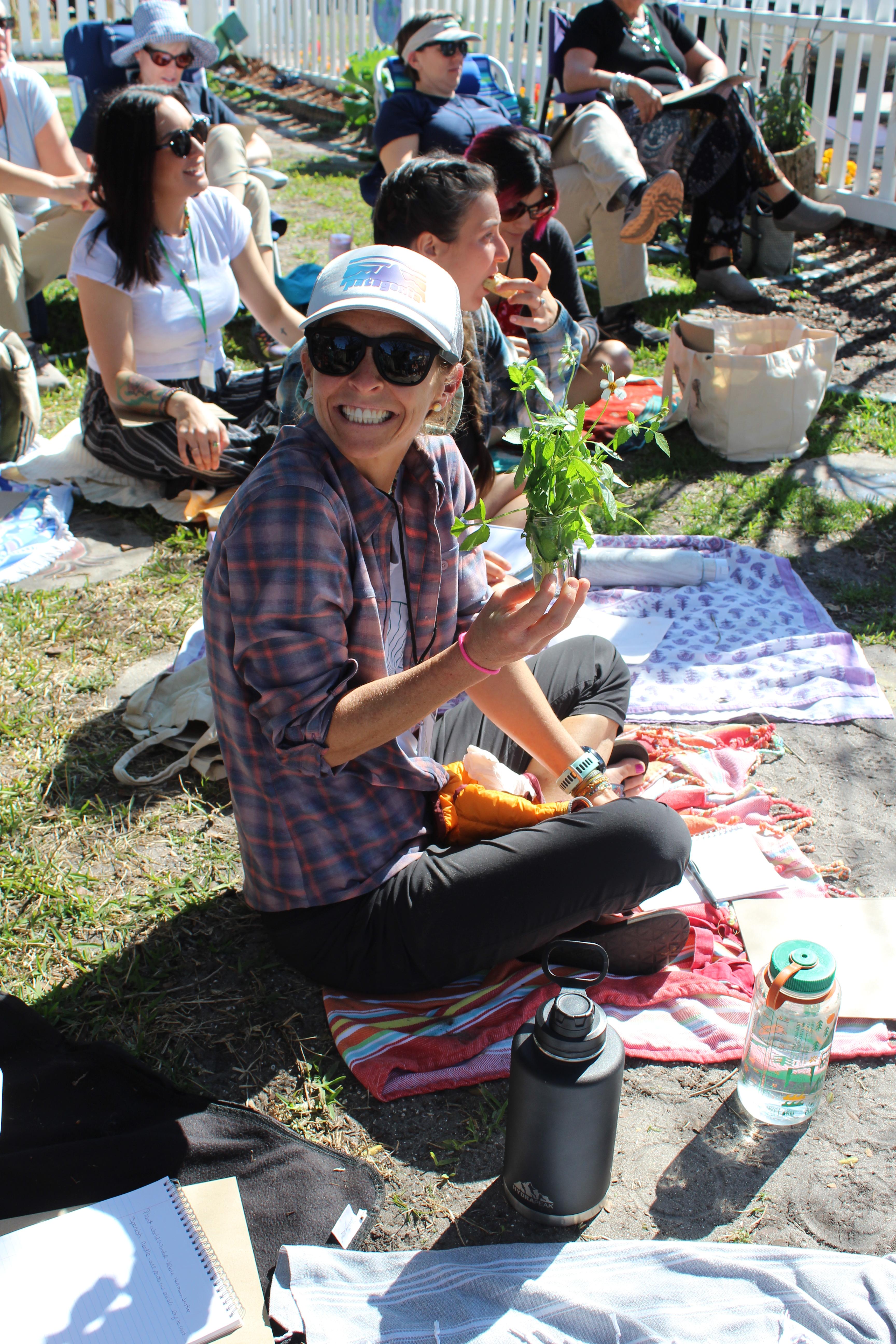 Teacher smiles and holds a plant.